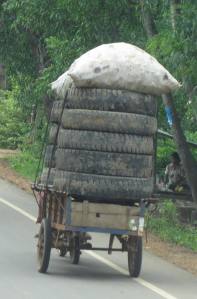 Tyres transported by moto-driven trailer.  It's unusual that there is noone sitting atop the load!