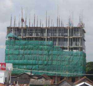 Workers with no hard hats, no harnesses, most in flip-flops, above rooftops in Kampong Cham